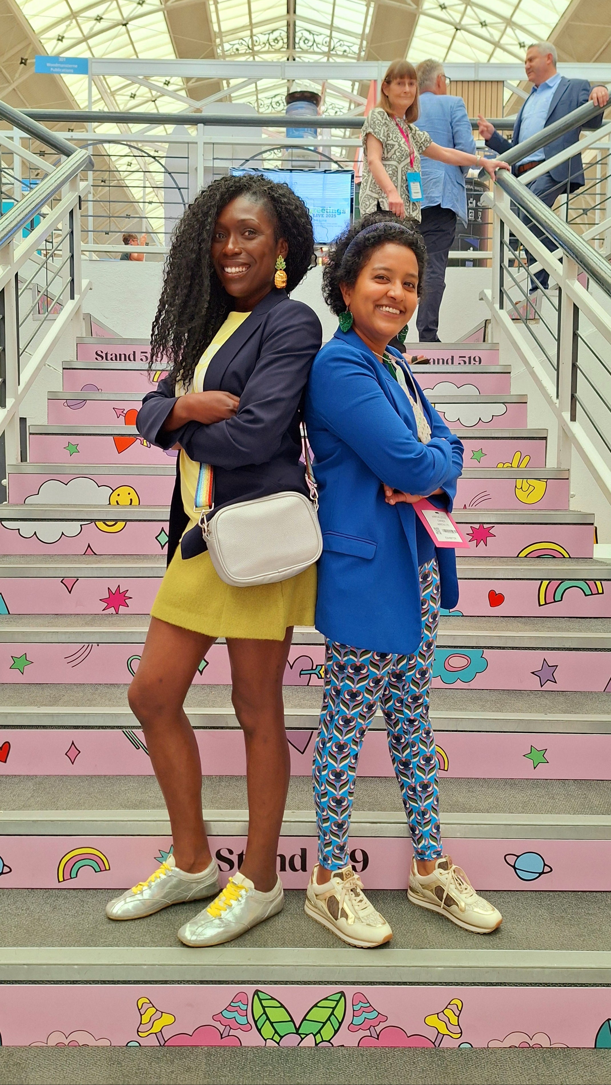 Adriana Lovesy and Arrthi Little standing on a colorful staircase at PG Live