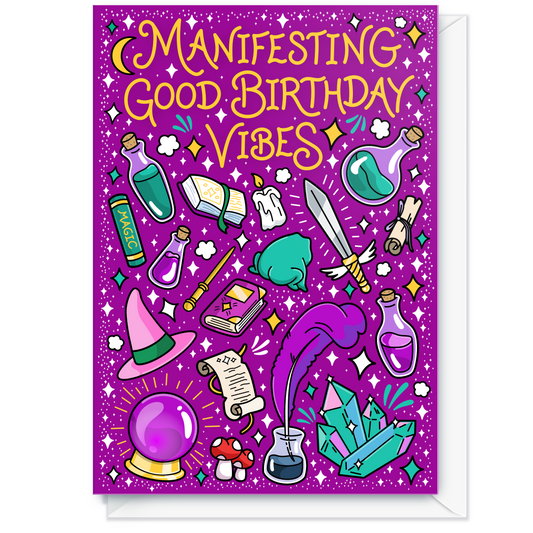 A purple greeting card with whimsical illustrated magic-themed elements and the text 'Manifesting Good Birthday Vibes' in yellow, shown with a white envelope behind it.